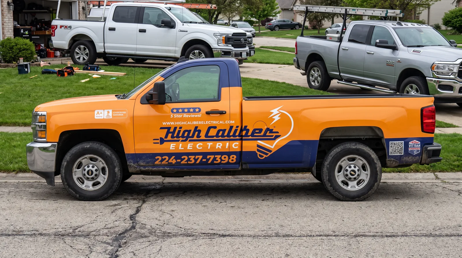 High Caliber Electric K3500 on a residential jobsite street. High Caliber ELECTRIC, 224-237-7398 on the navy rocker.