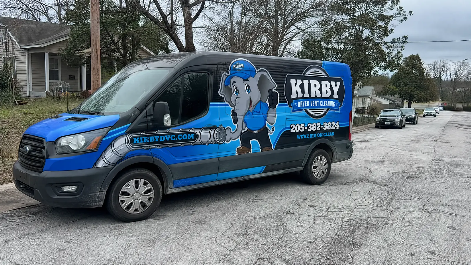 Kirby Dryer Vent Cleaning Transit van parked on a suburban street, elephant mascot and 205-382-3824 readable on the side.